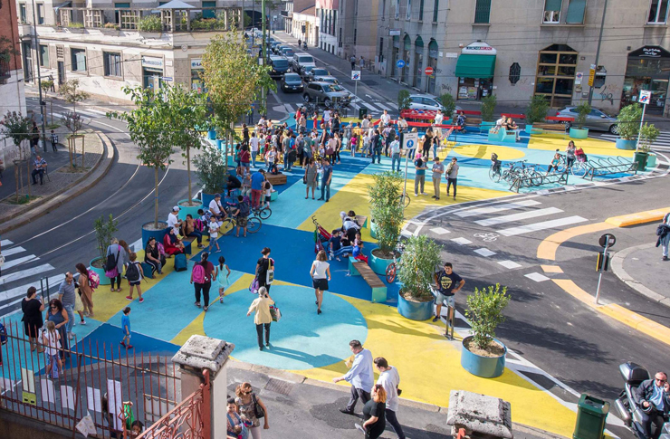 Piazza con colorazione a terra. Modifica della viabilità ha permesso di creare un'isola pedonale, percorsa da persone a piedi e in bici.