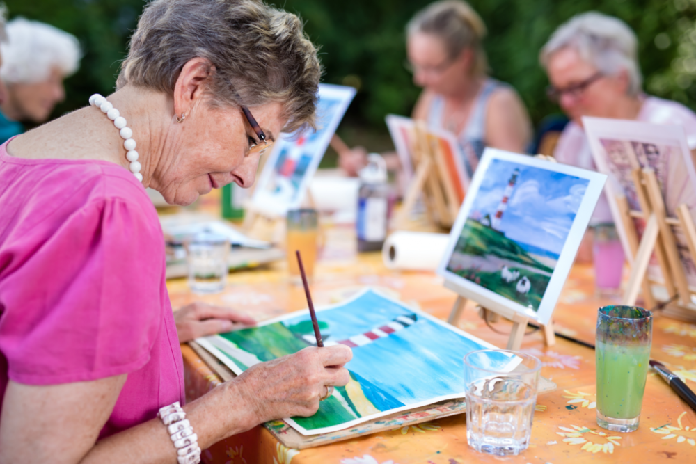 Donne anziane sedute ad un tavolo che dipingono