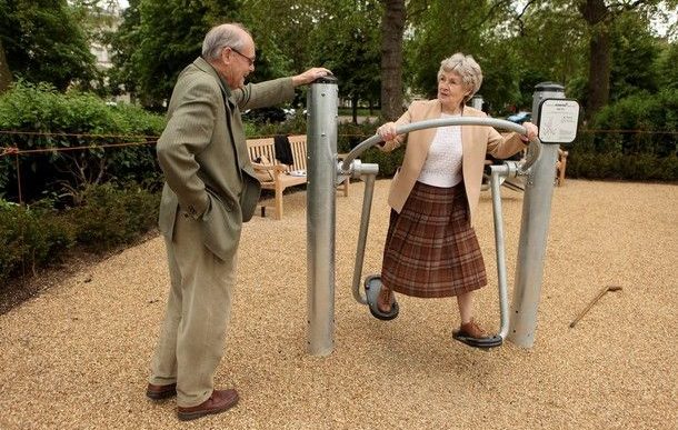 Due anziani fanno esercizio fisico all'aperto, su un attrezzo in un parco
